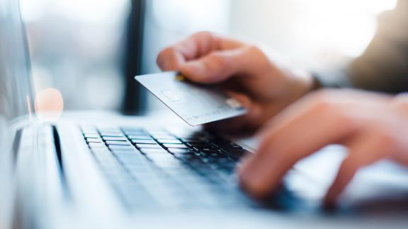 Man using laptop and holding credit card, close-up