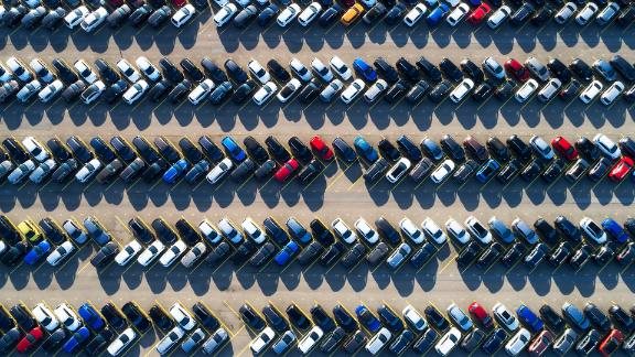 Aerial photograph of rows of cars parked in a large parking lot.