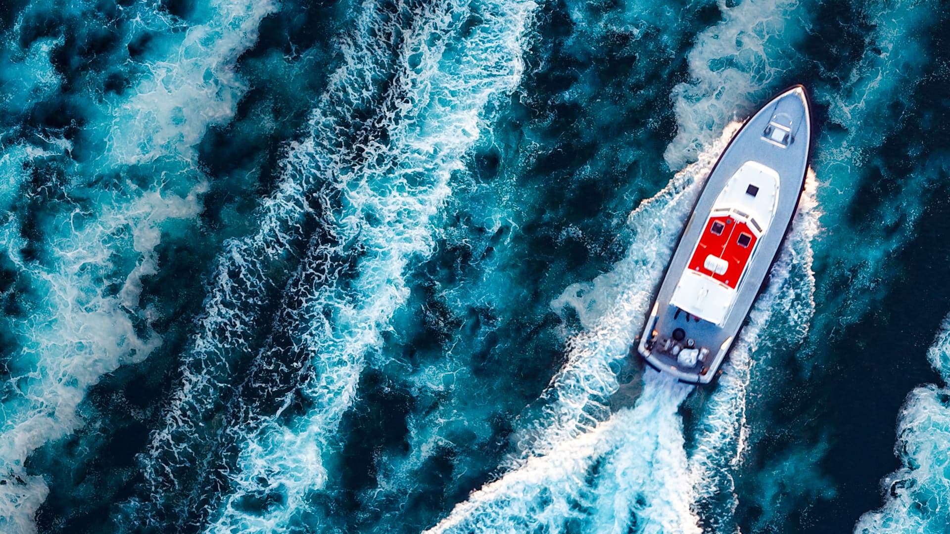 Aerial view of a motorboat surrounded by boat water wakes.