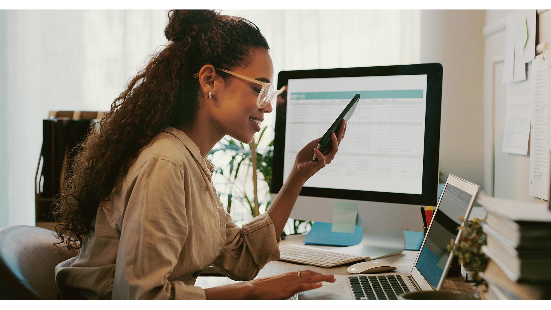 A woman multitasking at her desk in a home office.