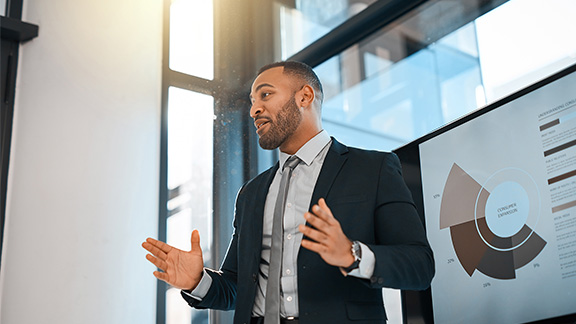 Shot of a young businessman presenting data on a screen during a meeting in an office