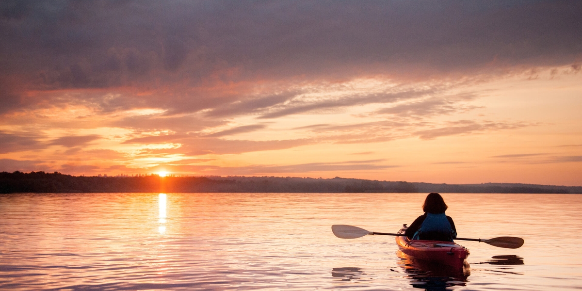 woman in a kayak on the river on the scenic sunset