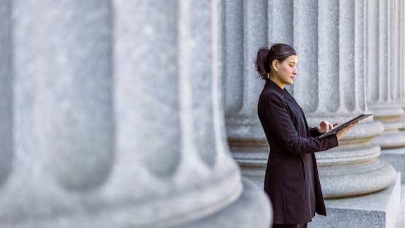 A business woman checking her notes for work outside of a government building.