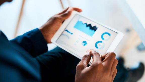 Cropped shot of a businesswoman using a digital tablet with graphs on it in a modern office