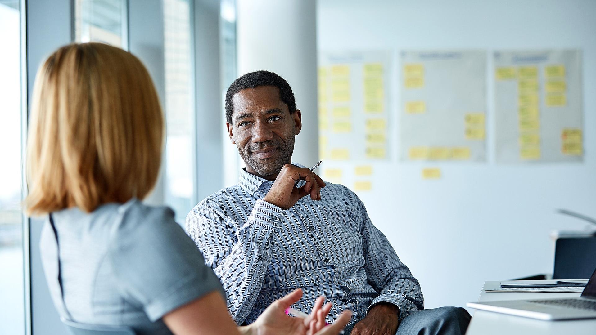 Shot of two colleagues talking together in a modern office