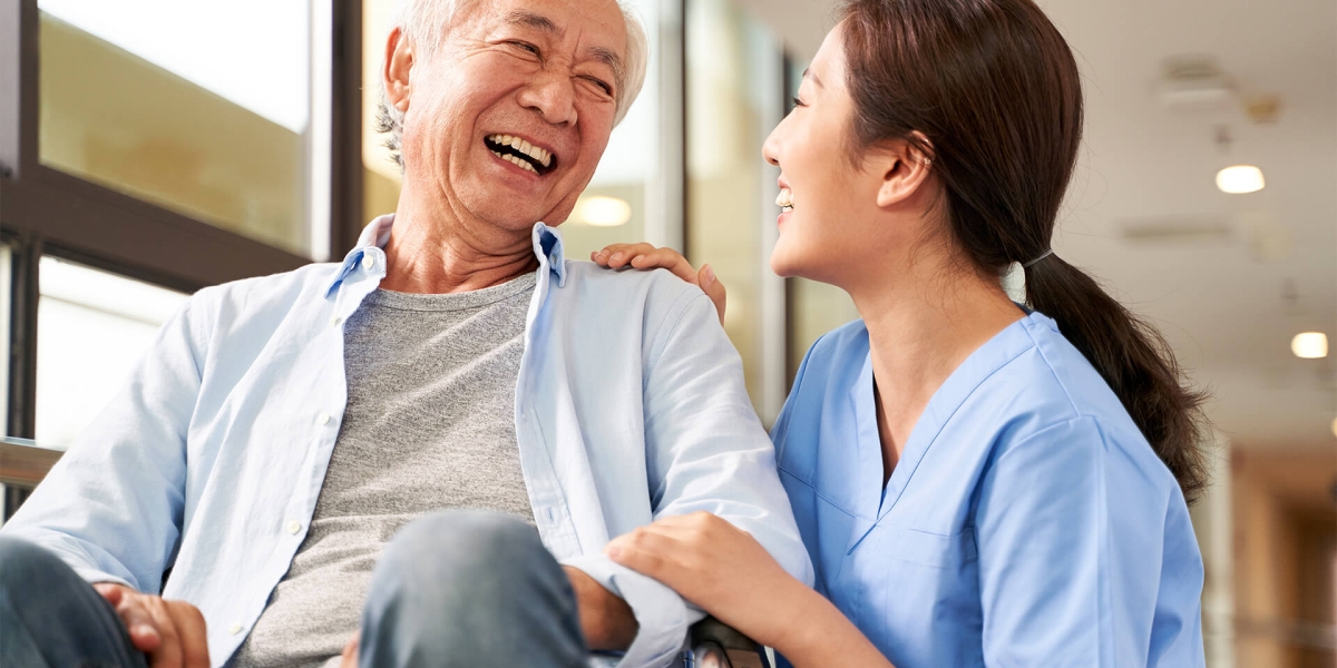 Friendly caretaker talking to senior patient in nursing home