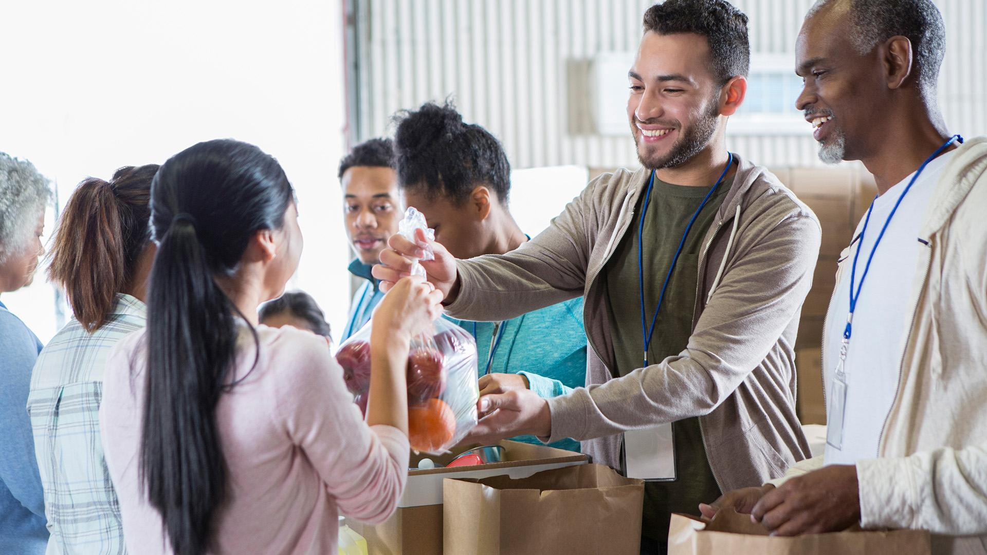 Diverse volunteers smile and talk before working on food drive 