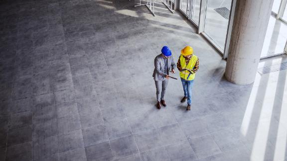 Top view of architect holding tablet and talking with construction worker about new ideas on project they working on. 