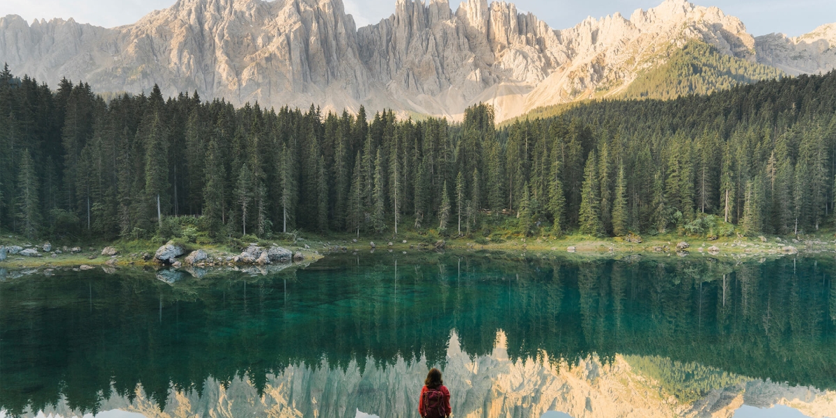 woman standing and looking at lago di carezza in dolomites