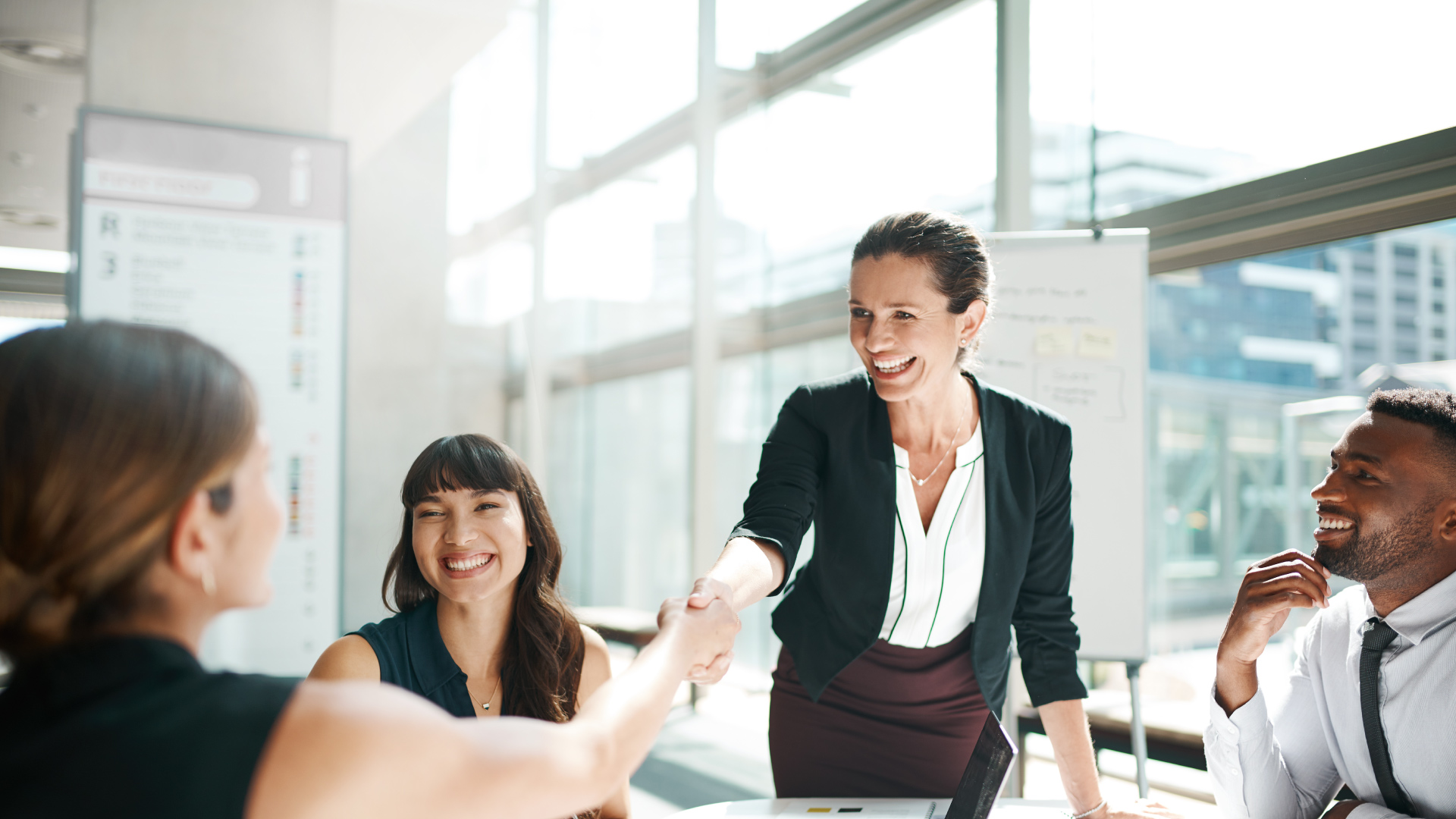 Shot of colleagues shaking hands in a meeting