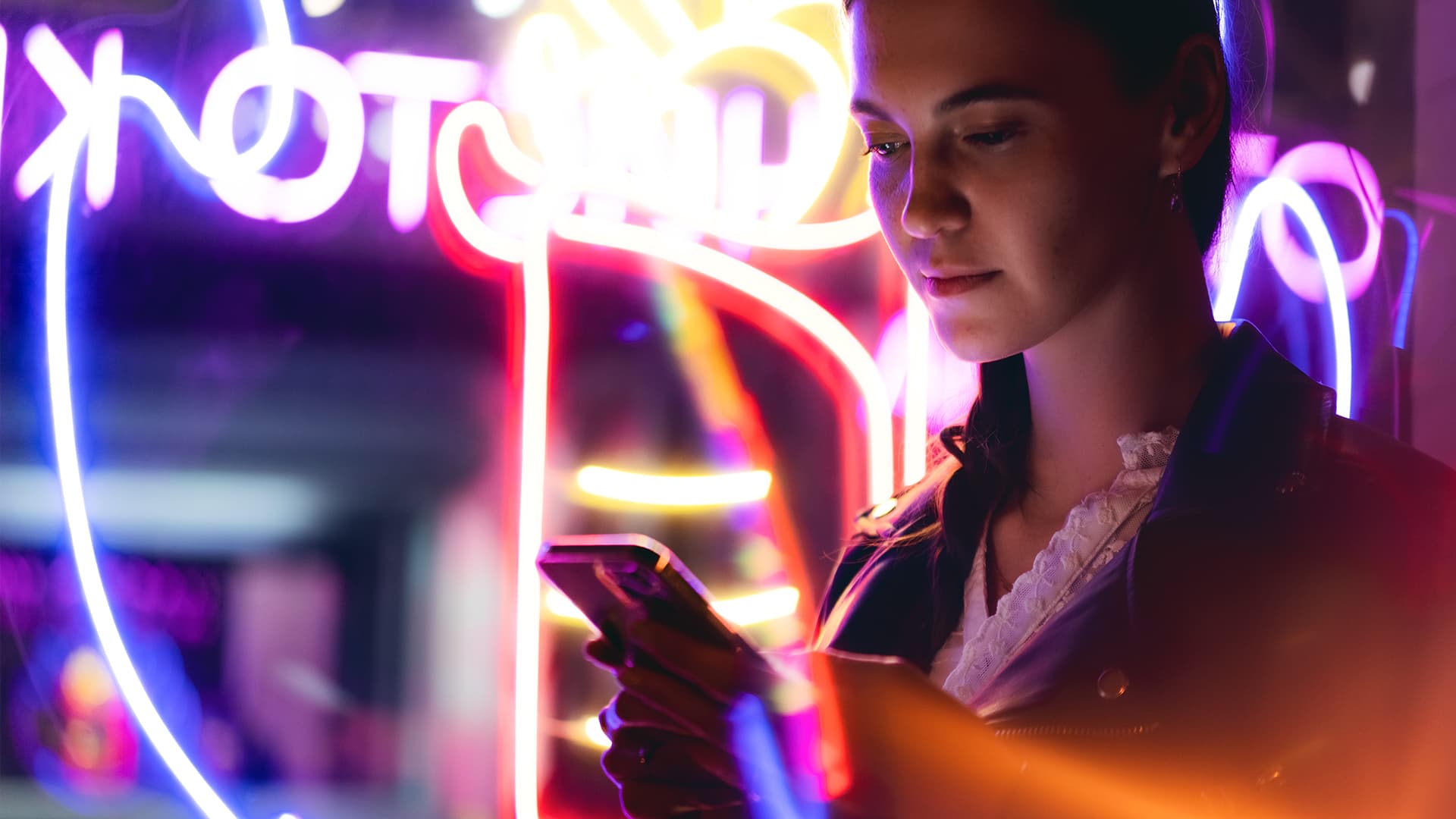 woman is using mobile phone at night in neon lights