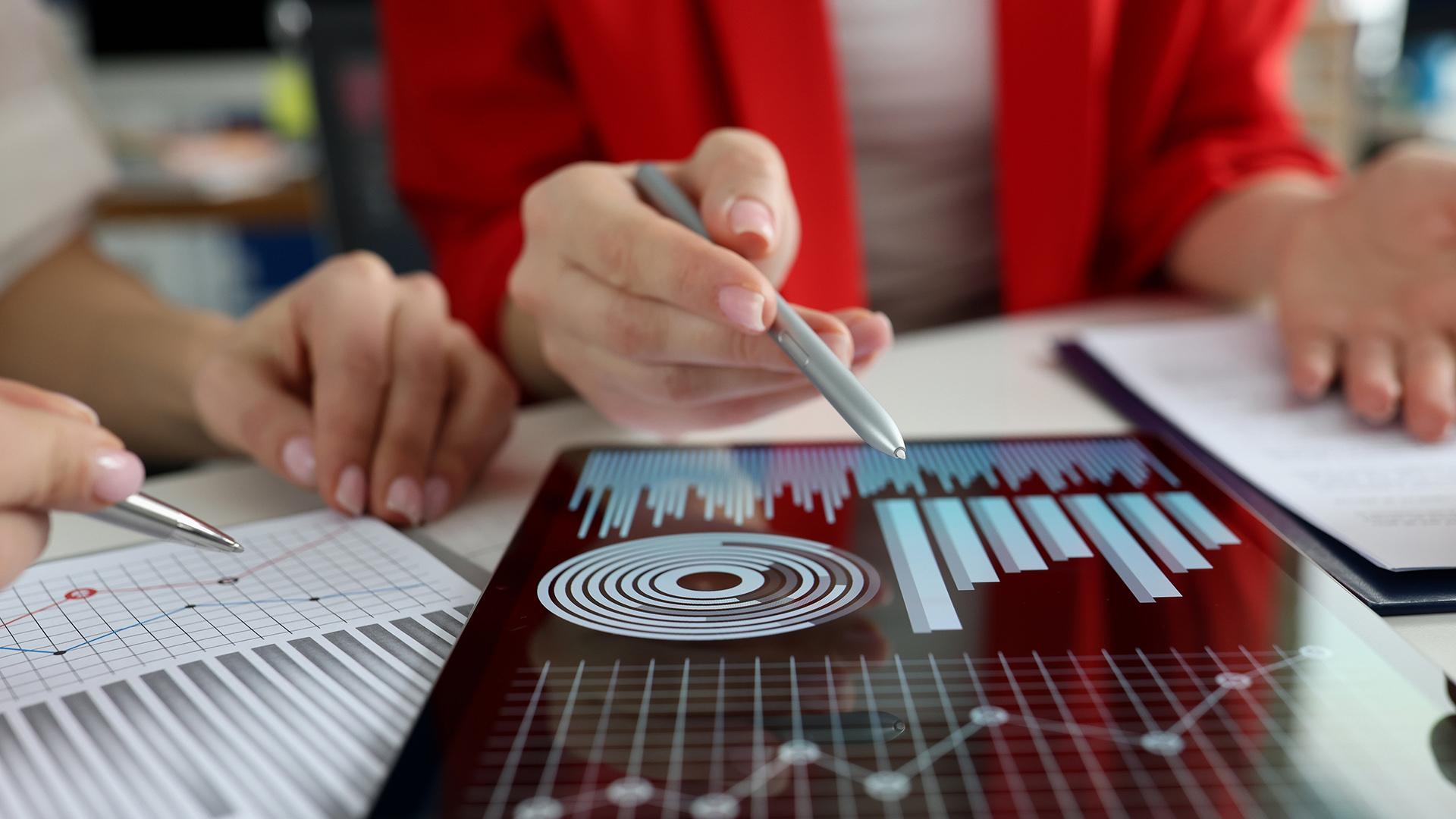 Business women studying charts and diagrams on digital tablet closeup