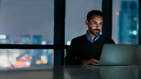 Man viewing laptop computer in office at night