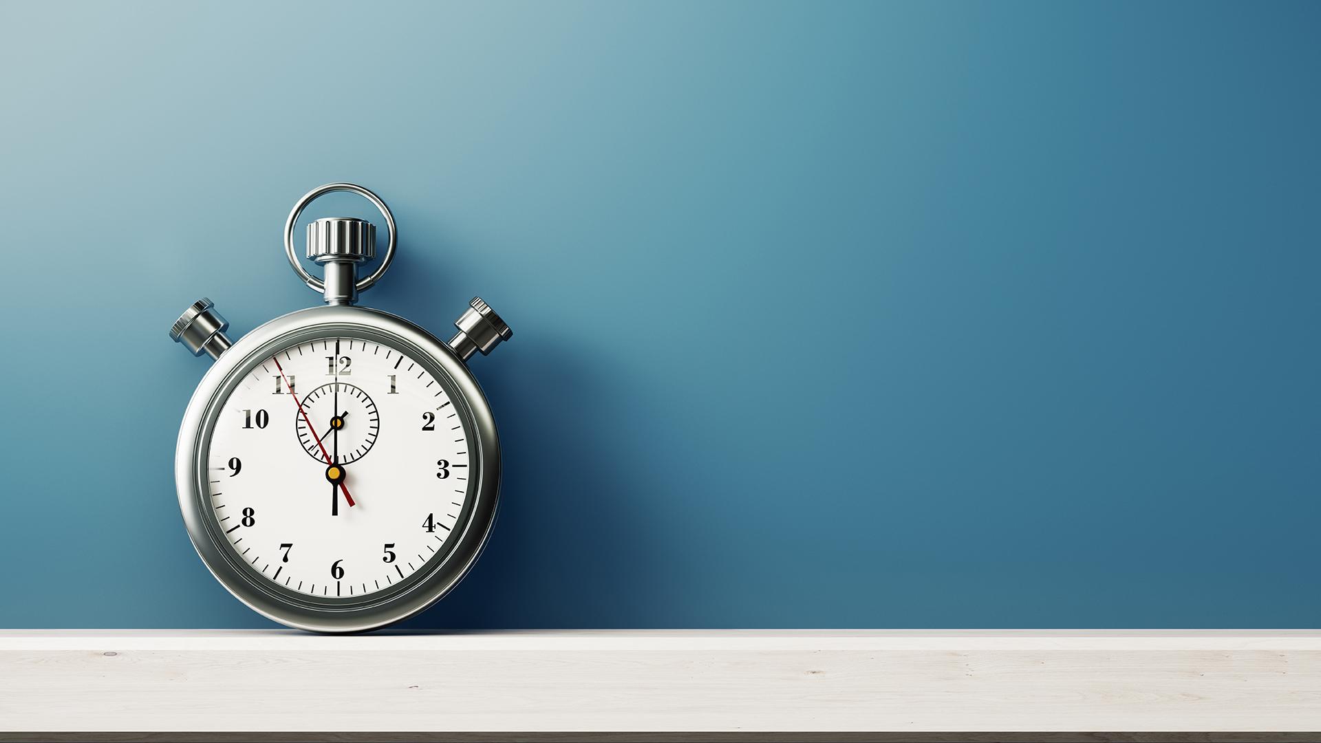 Silver Colored Stopwatch In Front of Blue Wall