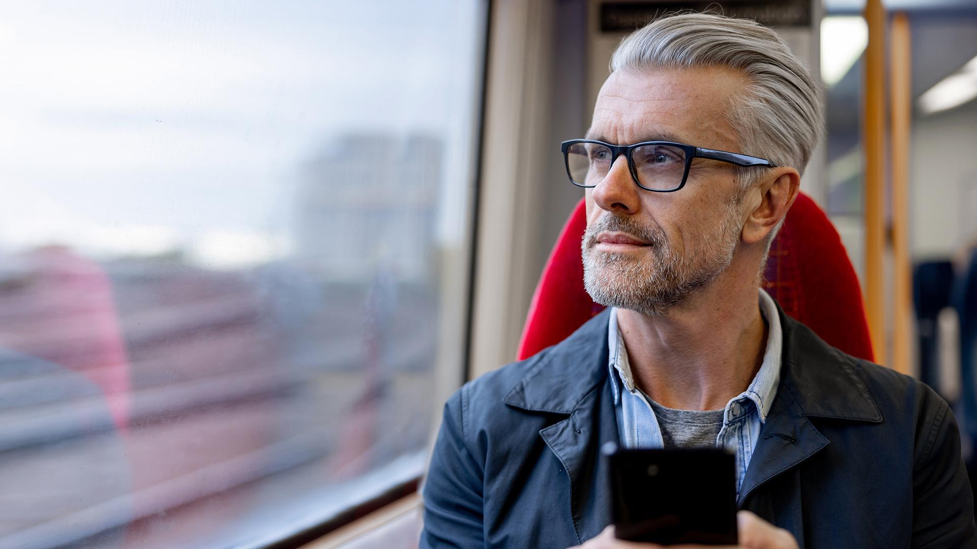 A man sitting on a commuter train, gazing out the window.