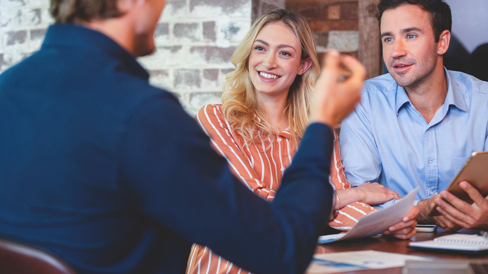 Young couple meeting with an advisor or business person. They are holding documents and talking.