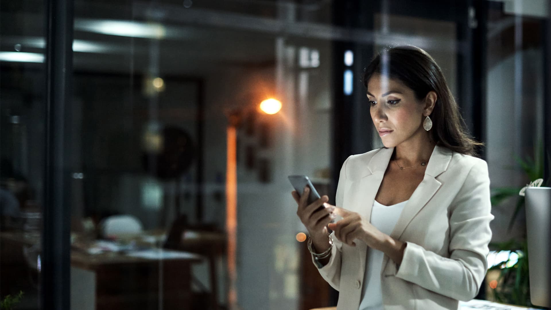 Shot of a young businesswoman using her phone at work