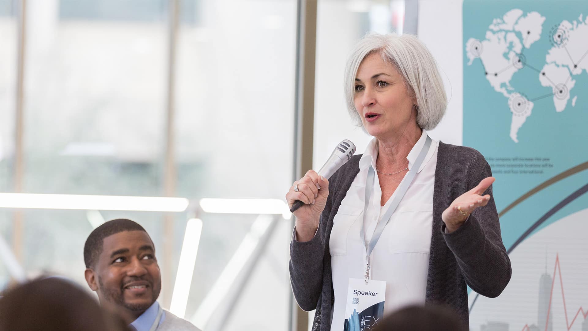 As fellow panelists look on, the mature adult female presenter speaks about global issues