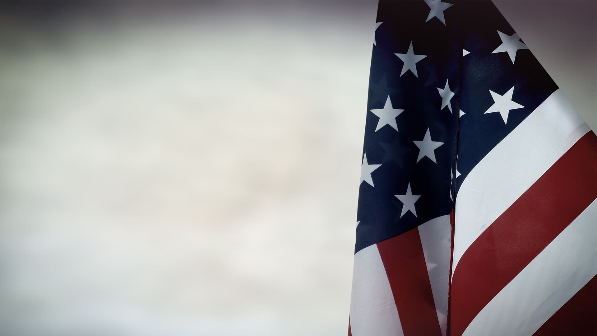 An american flag with grey skies.