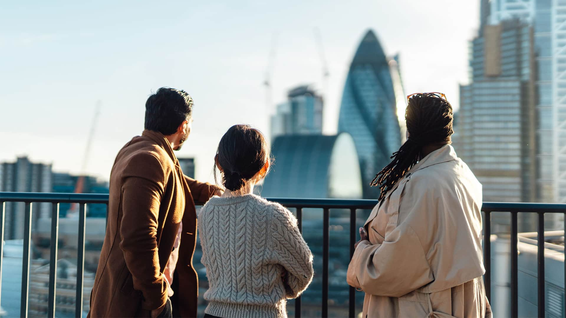 Rear view of business people standing on rooftop in an office building against cityscape.