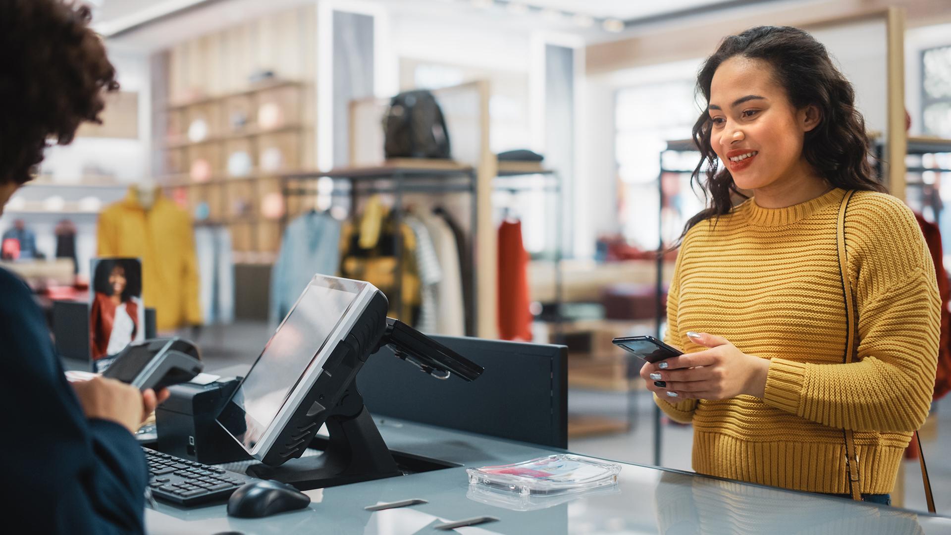 Woman in a yellow sweater checking out at a cash register