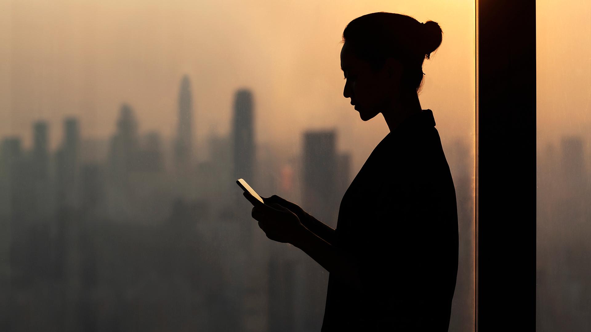 A woman looking at her phone in a highrise office.