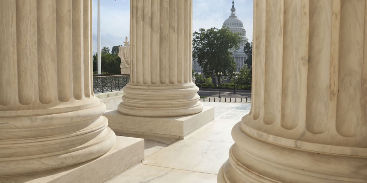 View between three large, white columns looking toward the U.S. Capitol building.