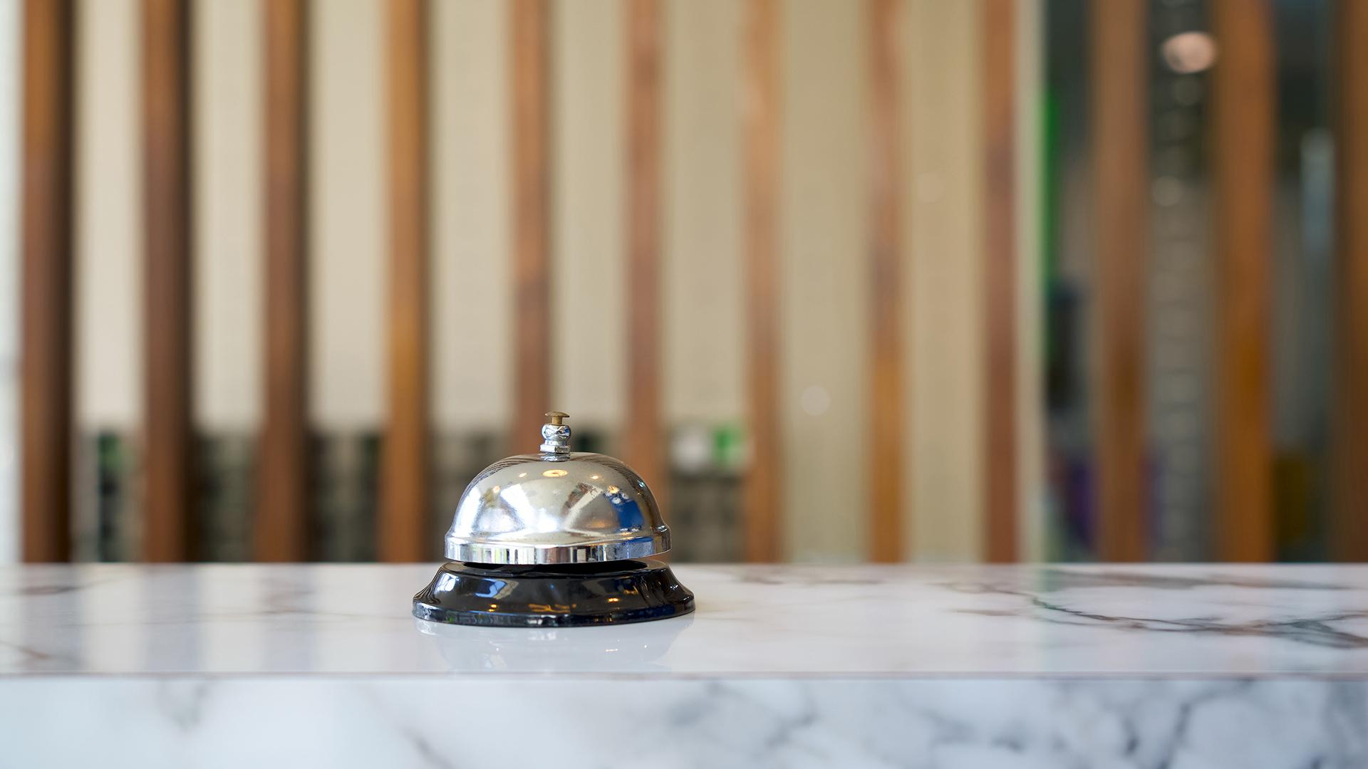 A hotel desk bell on a marble counter top.