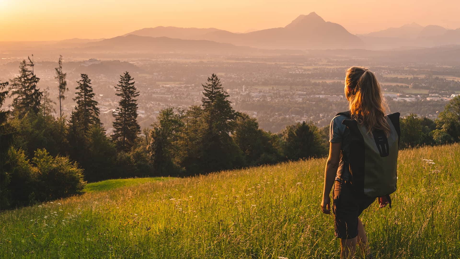 Female hiker relaxes on grassy mountain ridge