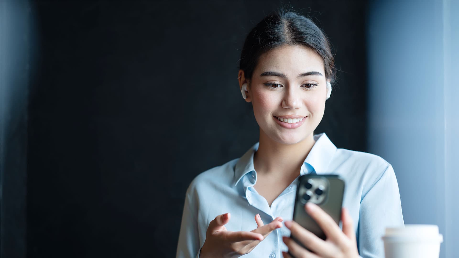 Businesswoman answering or conference call with her business partner on a smartphone in an office space.