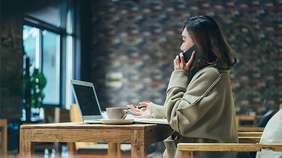 Small business owner on her laptop and chatting on cellphone.