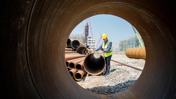 A female engineer used a measuring instrument to measure the quality of steel pipe