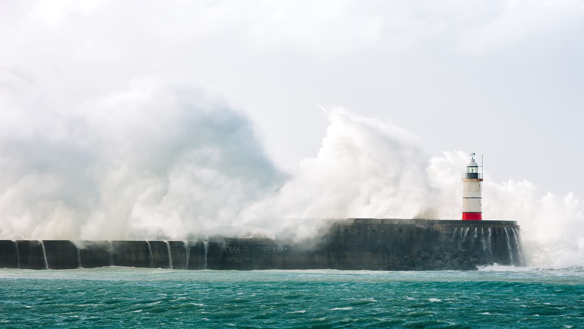 Ocean waves crashing into lighthouse.