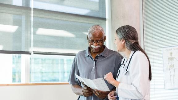 A doctor looking over a chart with a patient, smiling.