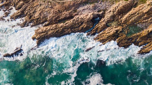 Aerial view of beautiful seascape. Waves are crashing on rocky coastline. Scenic view of ocean.