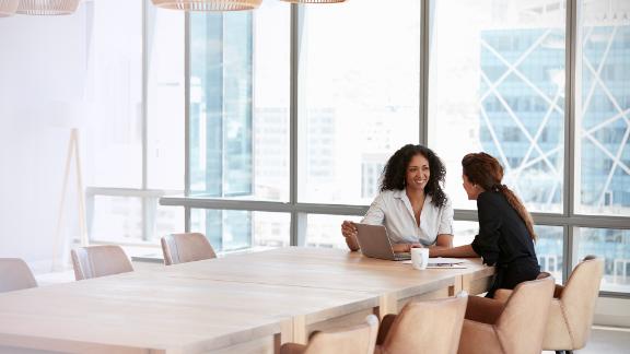 Two Businesswomen Using Laptop In Boardroom Meeting