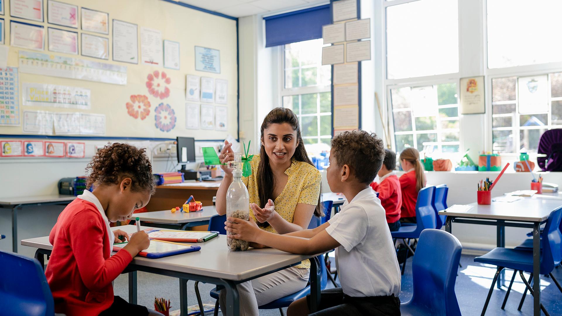 A teacher helping two kindergarteners with a special project.