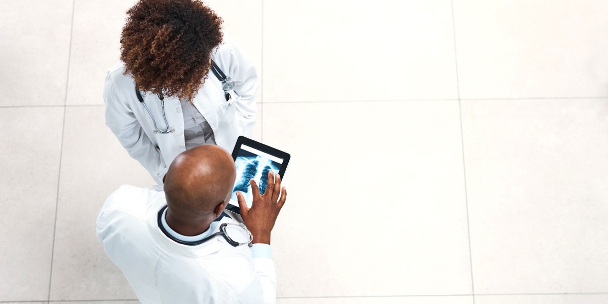 Two hospital workers examining a chest x-ray on an iPad.